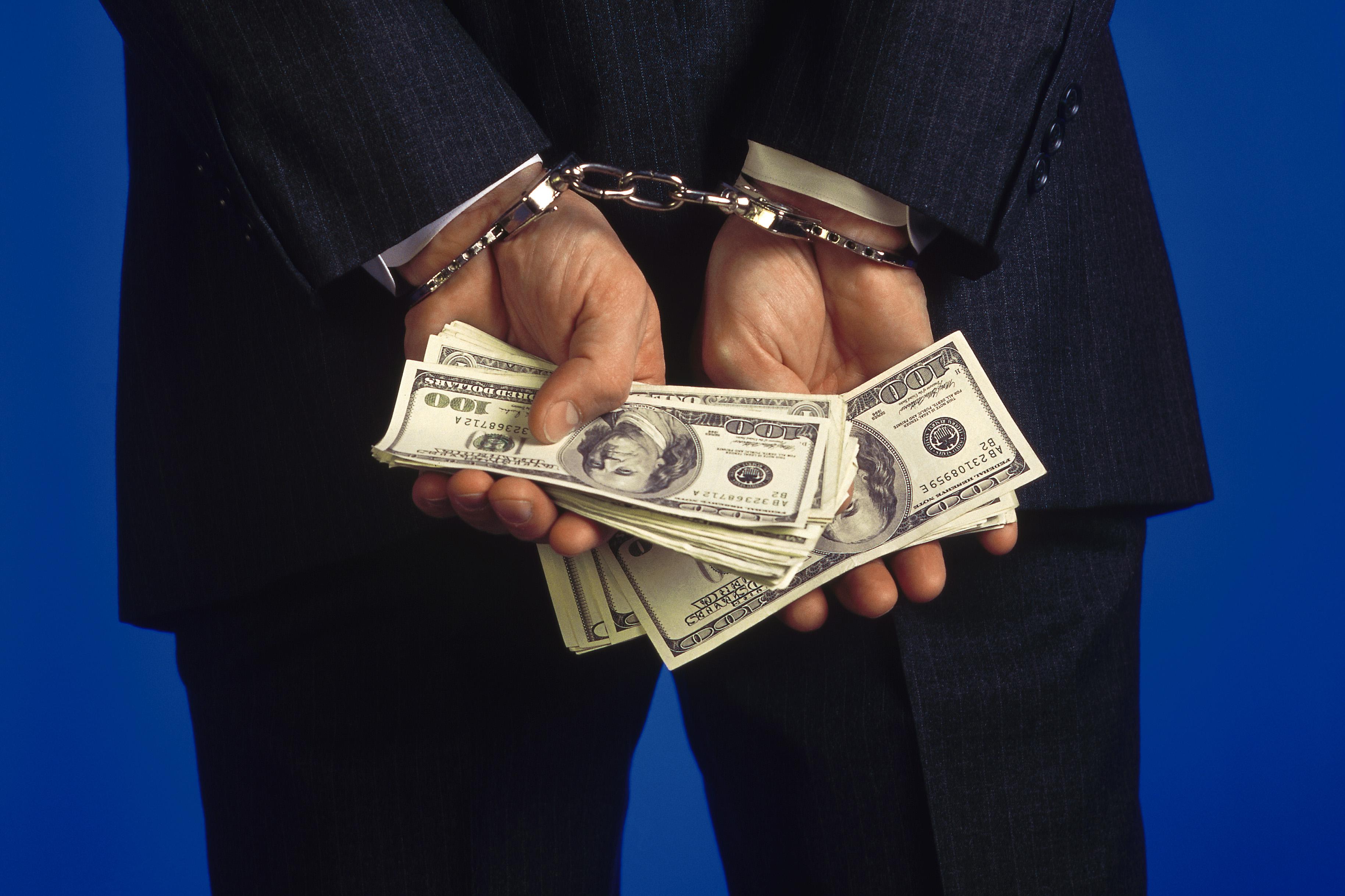 Handcuffed businessman holding cash