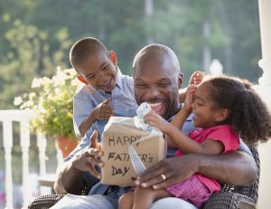 Boy and girl watching father open Father's Day gift
