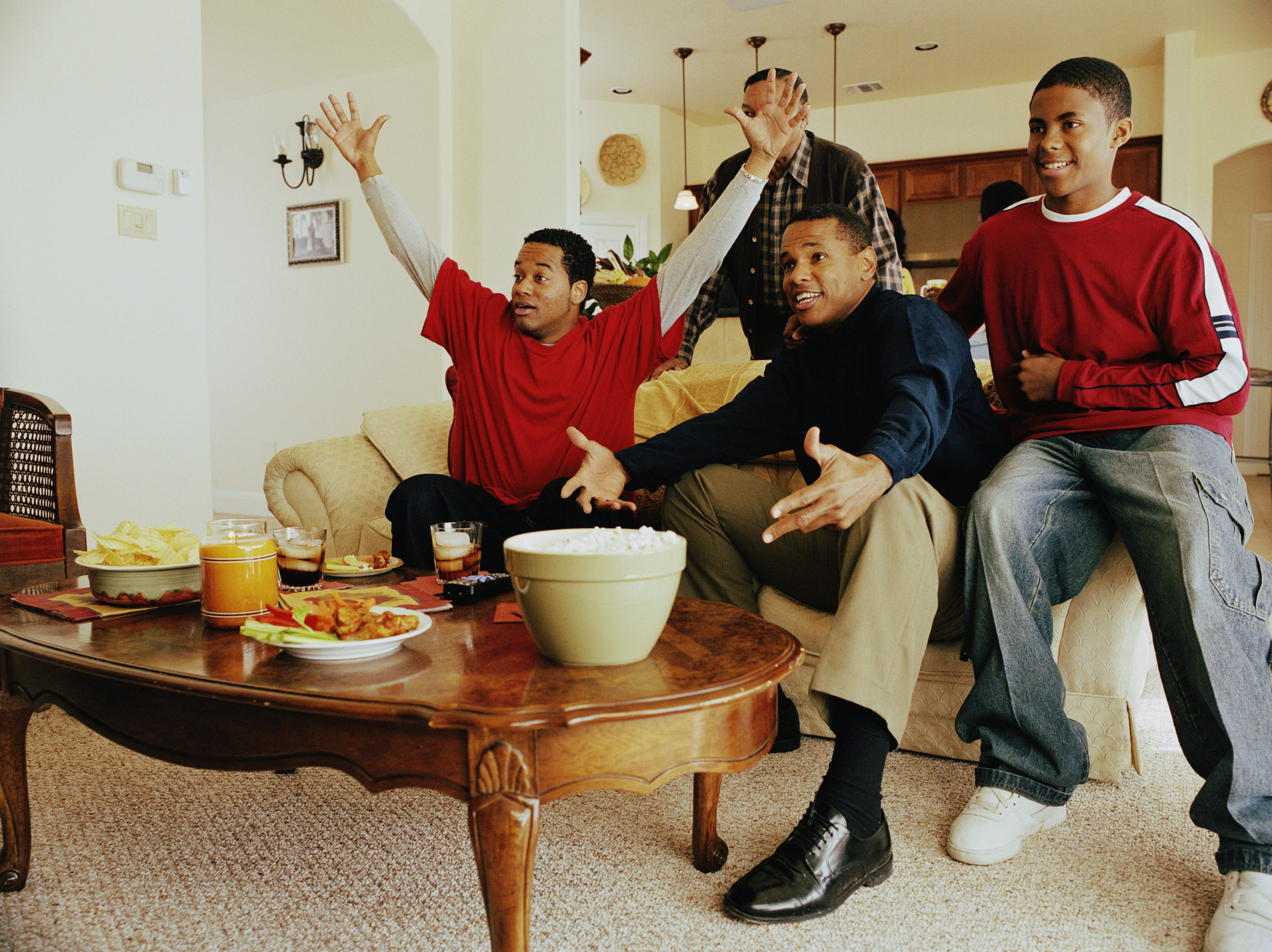 Three generations of men cheering in living room