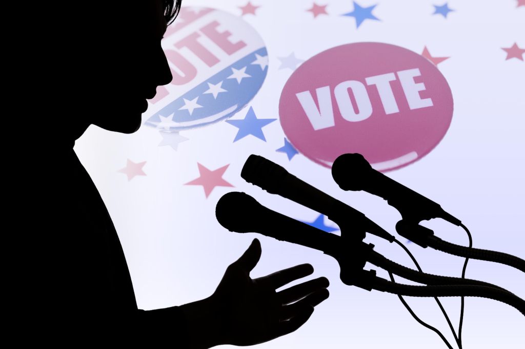 Silhouette of politician speaking before microphones