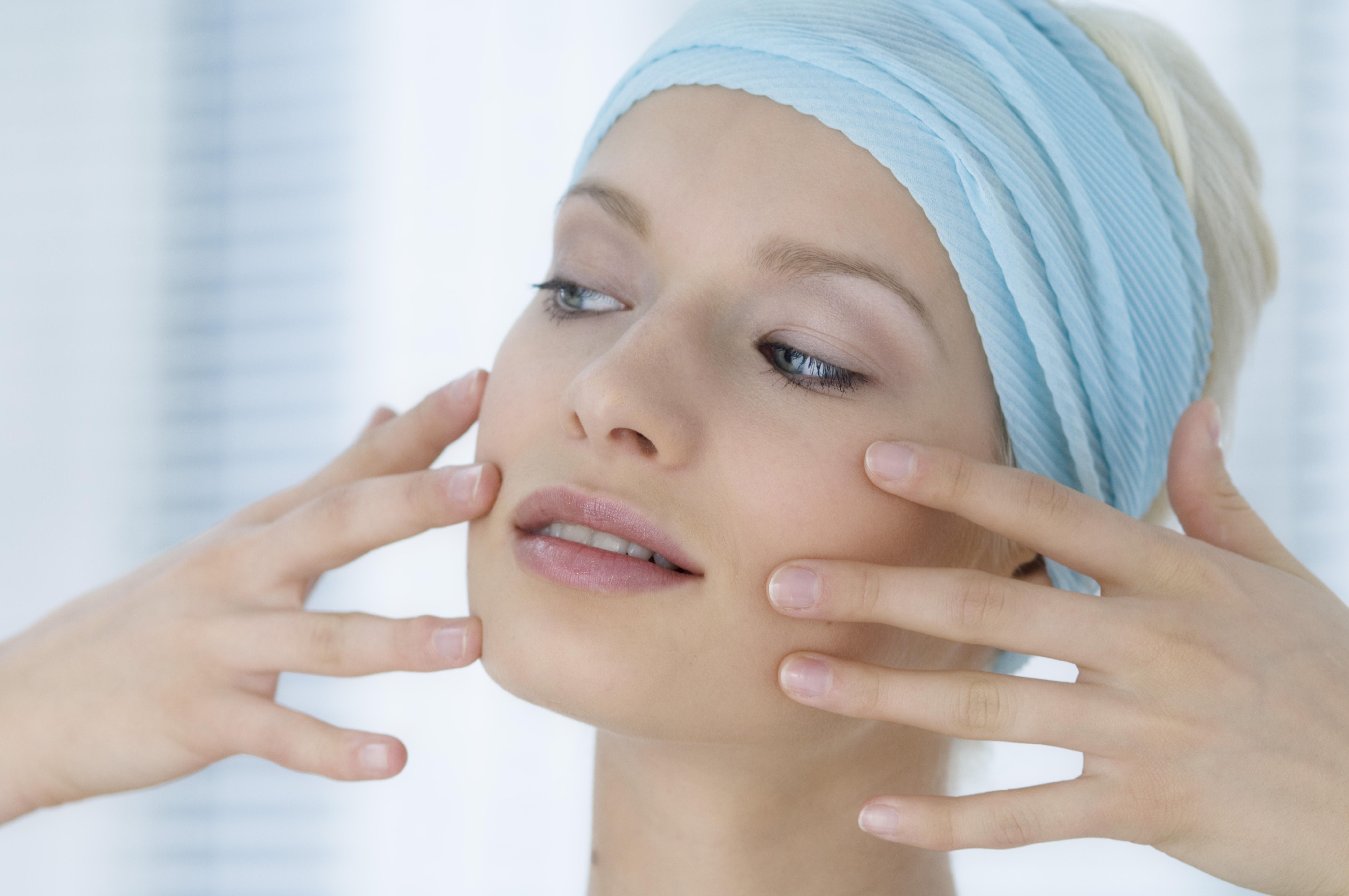 Young Woman face with make up, putting her fingers on her face, close-up (studio)