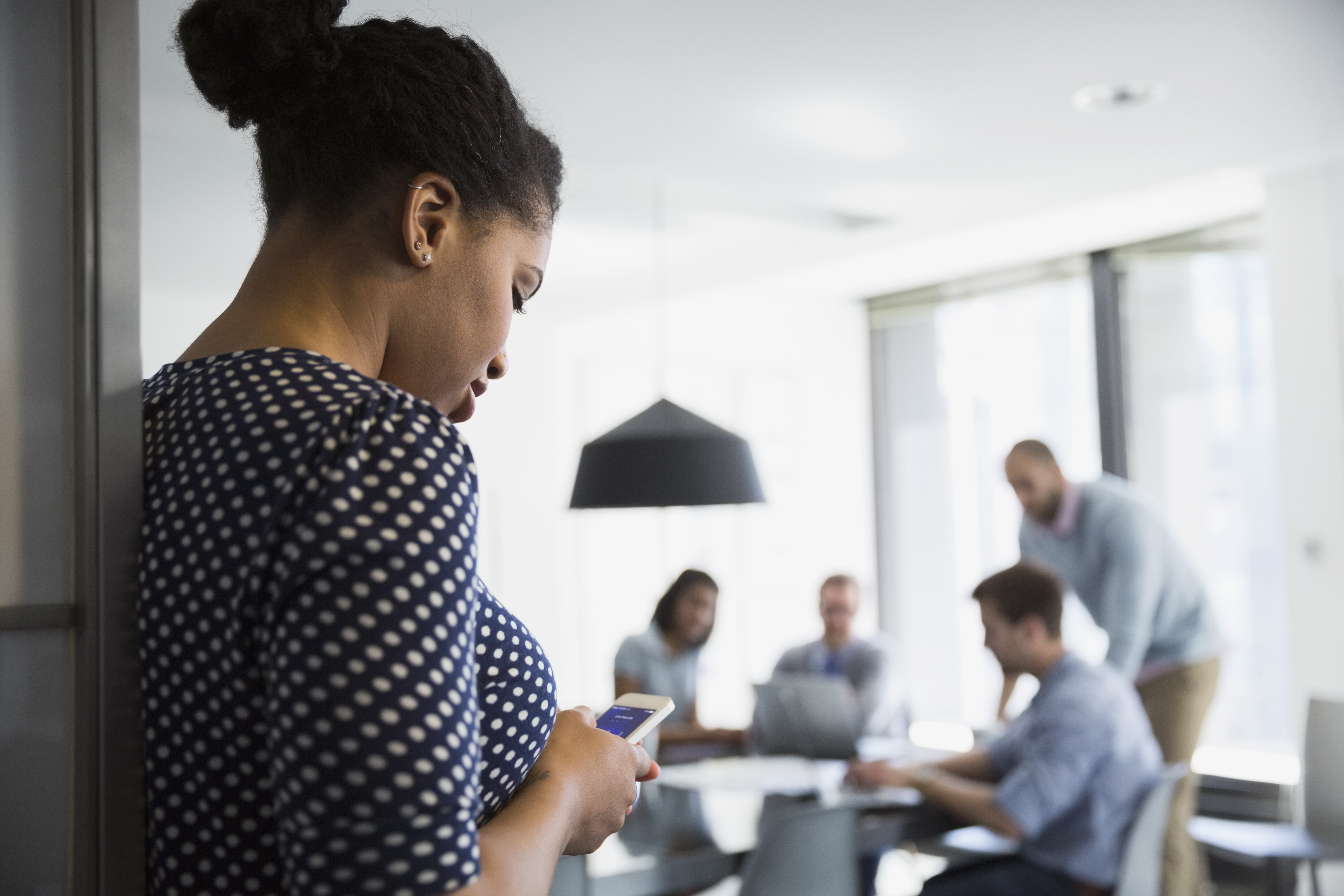 Businesswoman texting cell phone outside conference room meeting