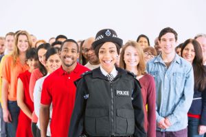 Portrait of smiling policewoman in front of large crowd