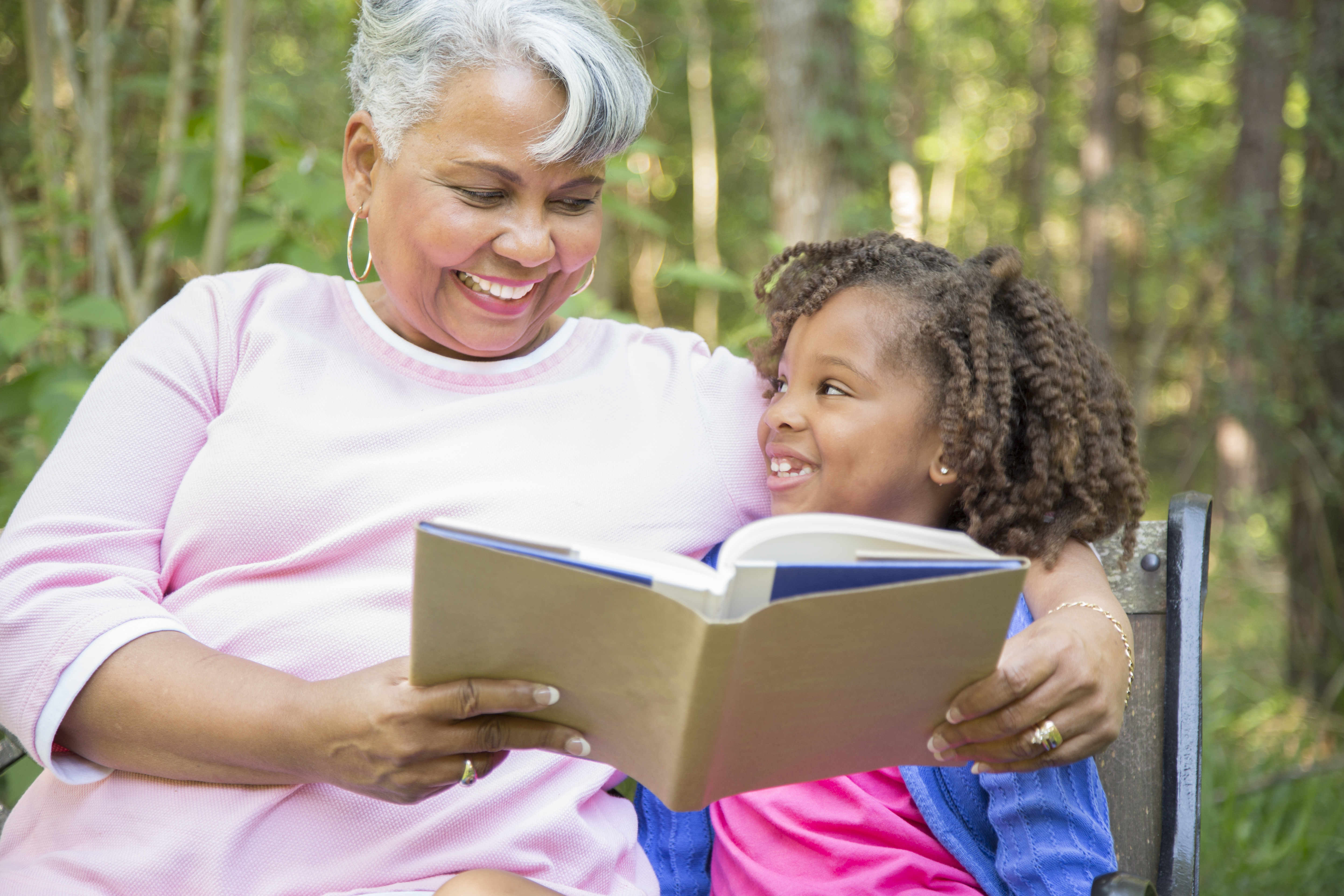 Grandmother and grandchild reading books outdoors together.
