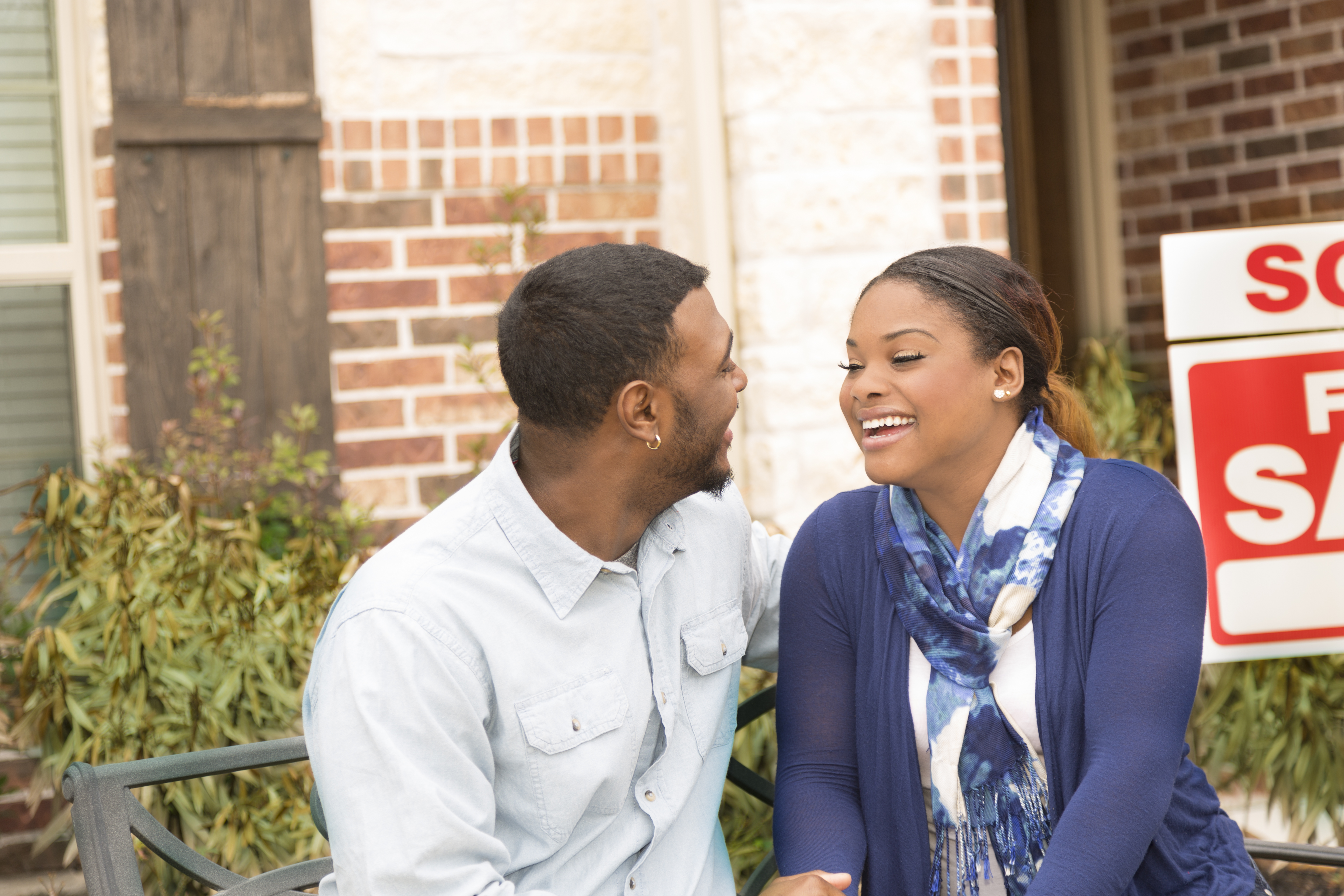 Excited couple in front of first home real estate purchase.