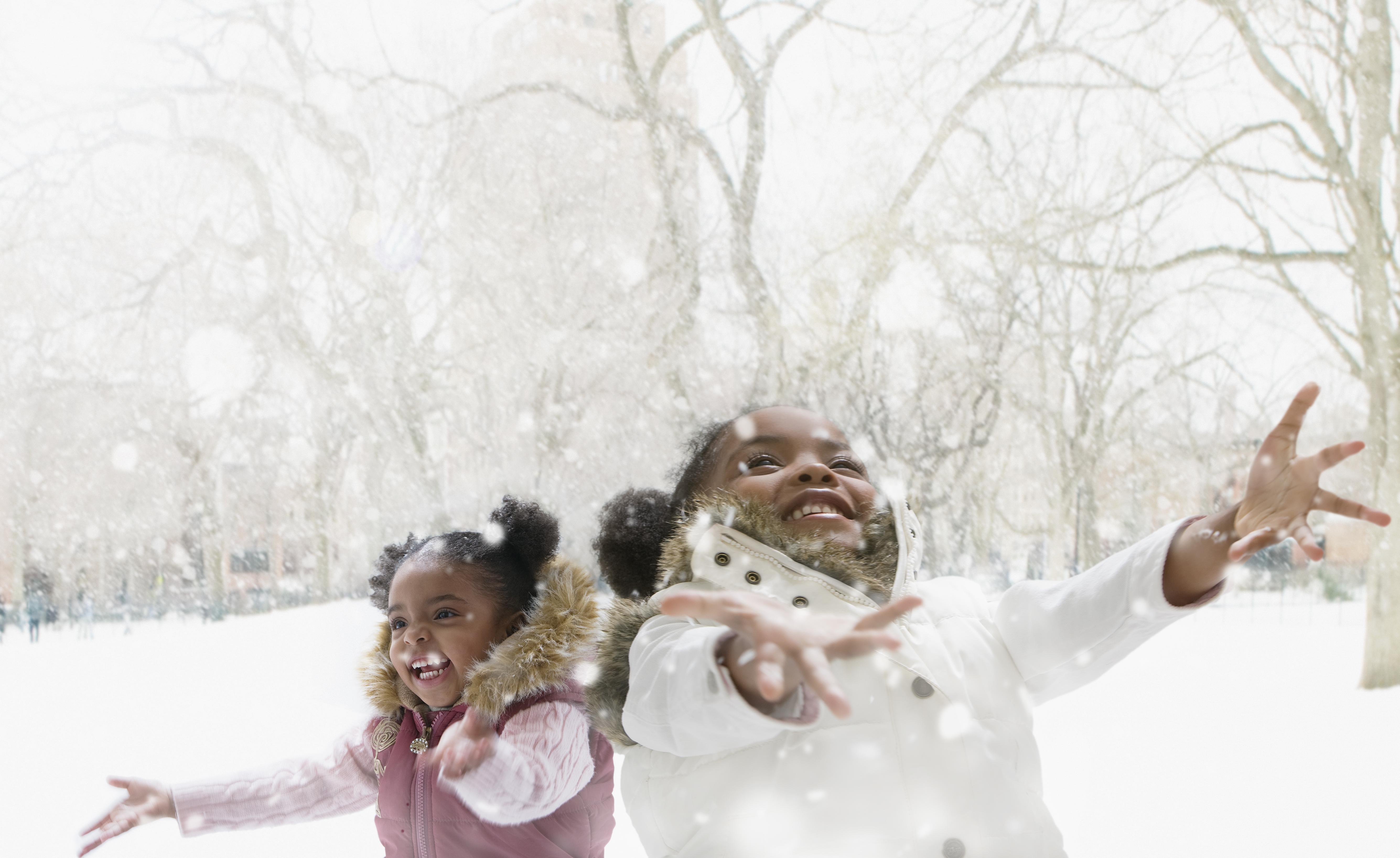 Mixed race girls catching snowflakes