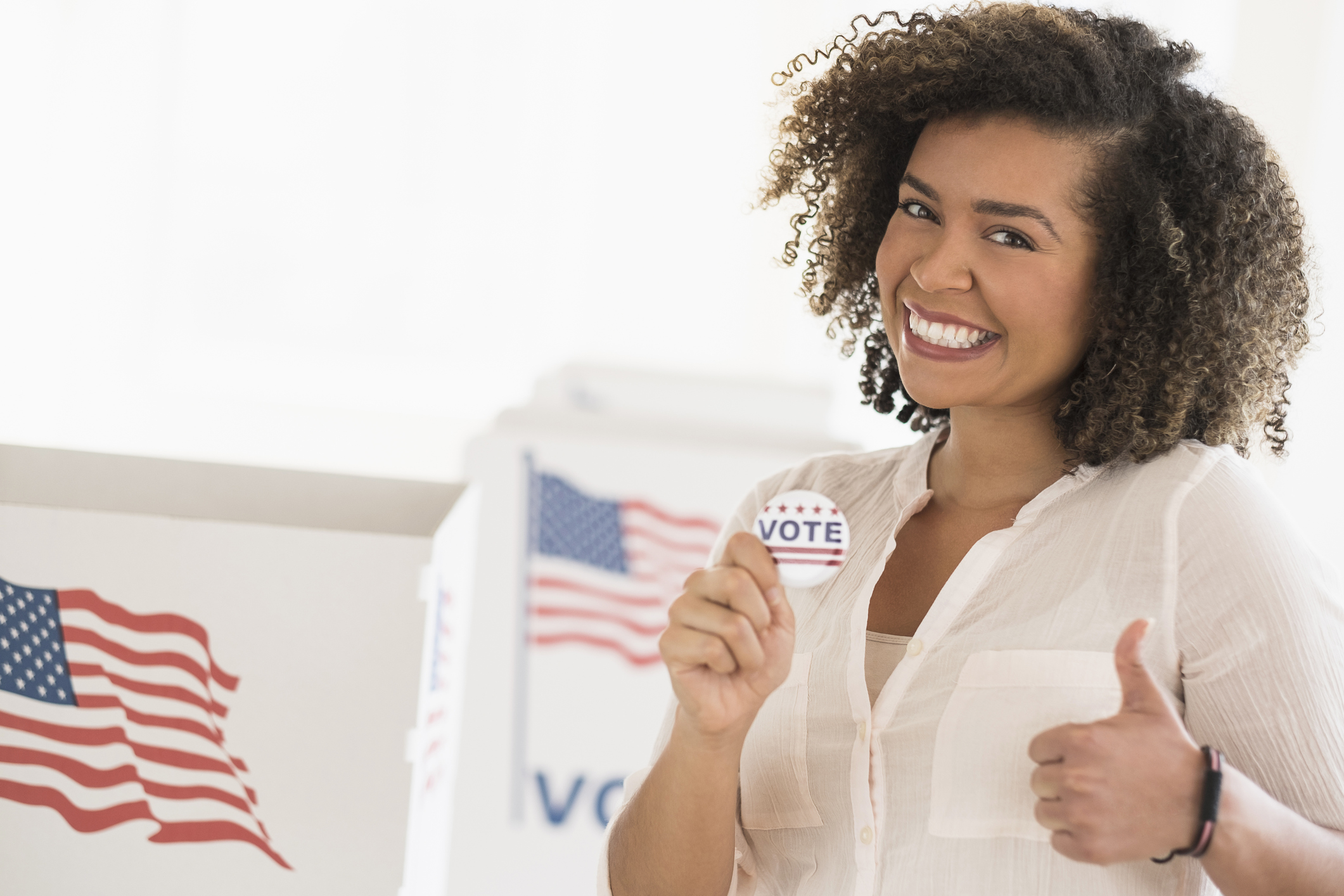 Young woman holding voting badge and smiling
