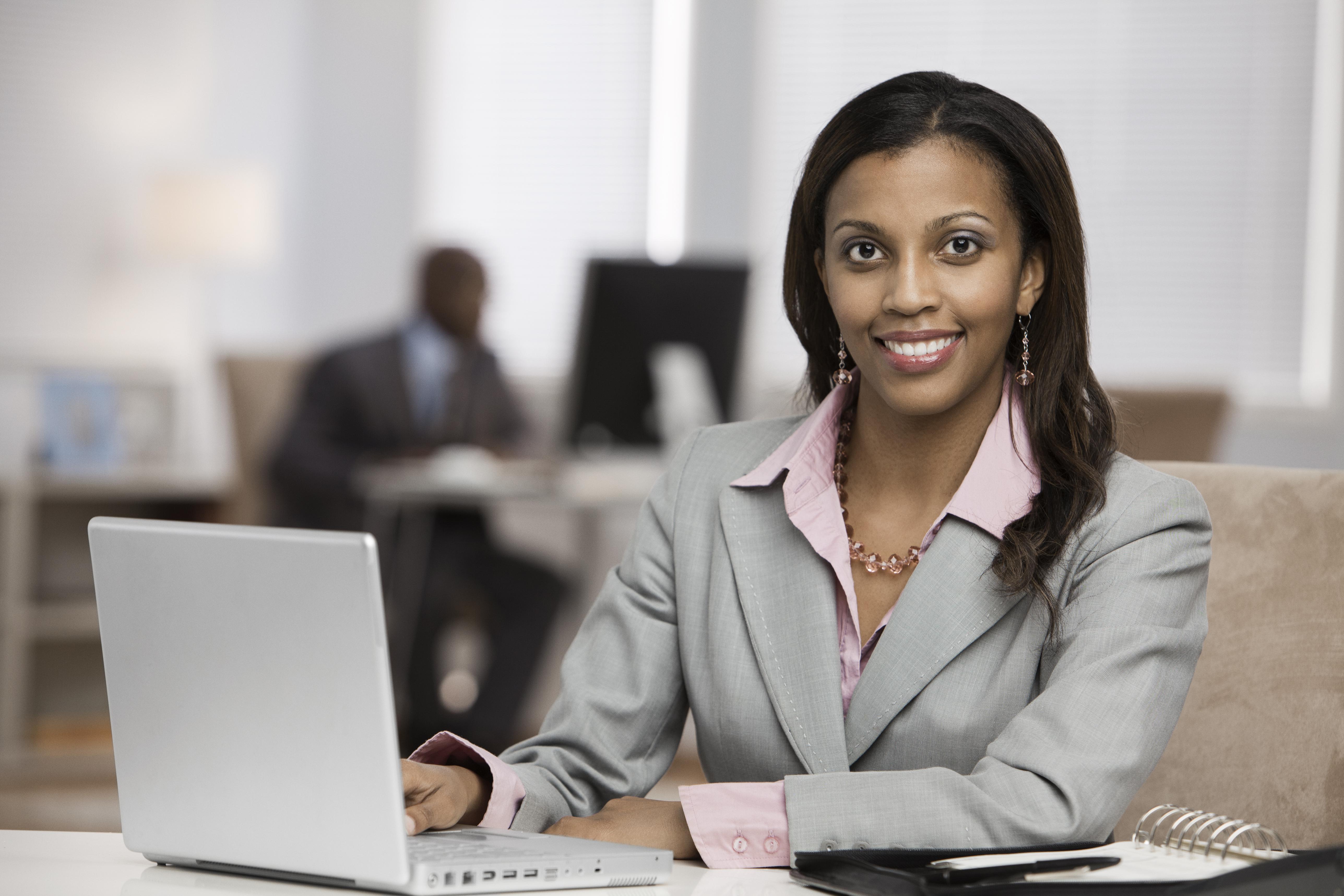 Mixed race businesswoman using laptop at desk