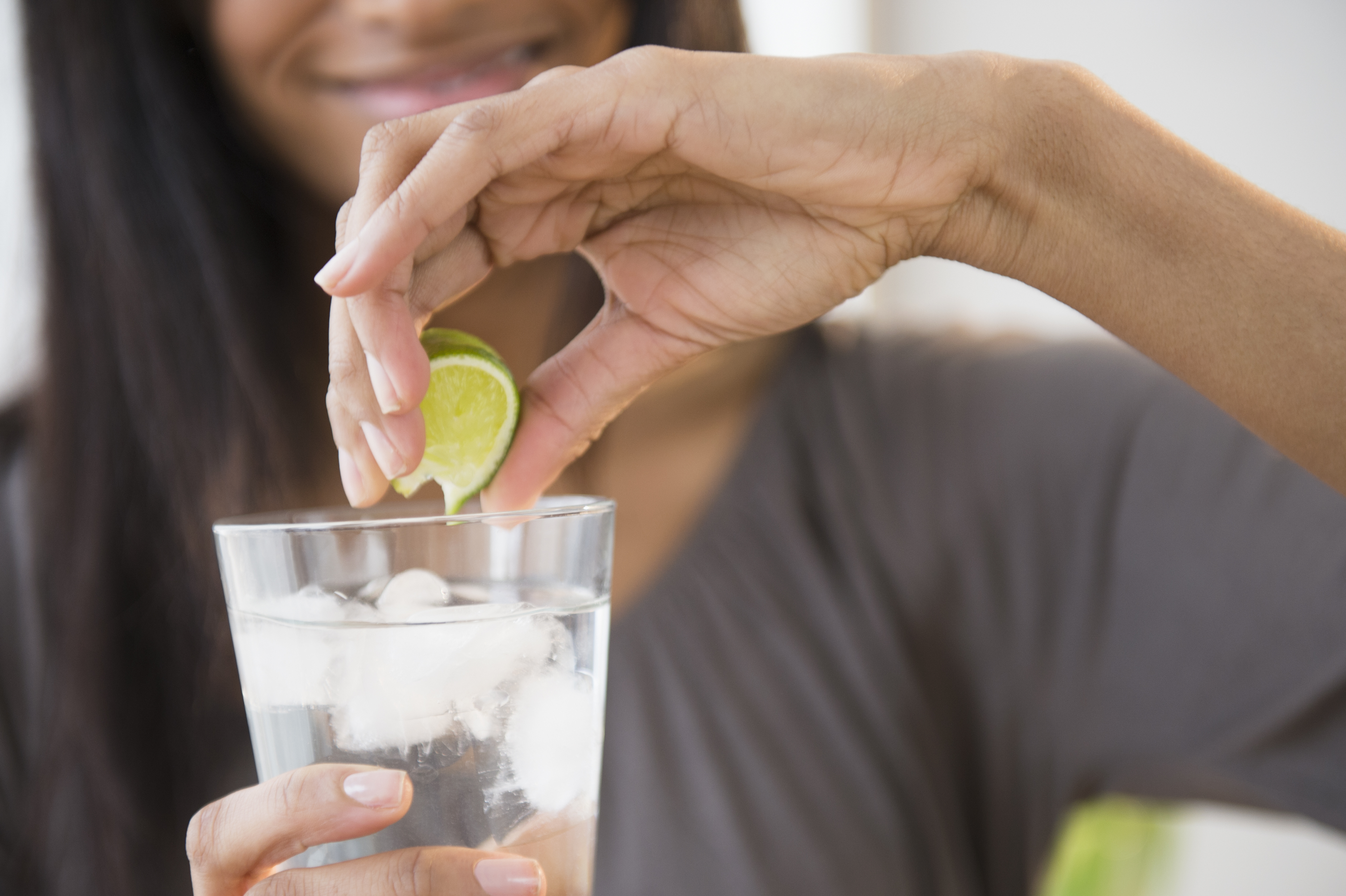 Mixed race woman squeezing lime into drink