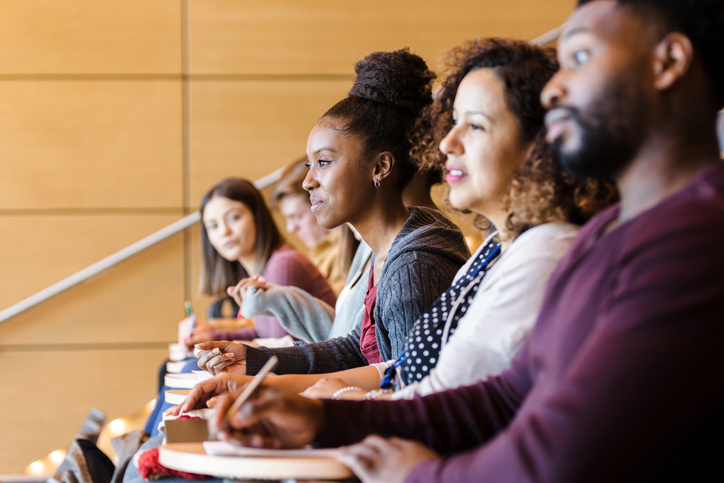 Diverse college students seated in row in lecture hall
