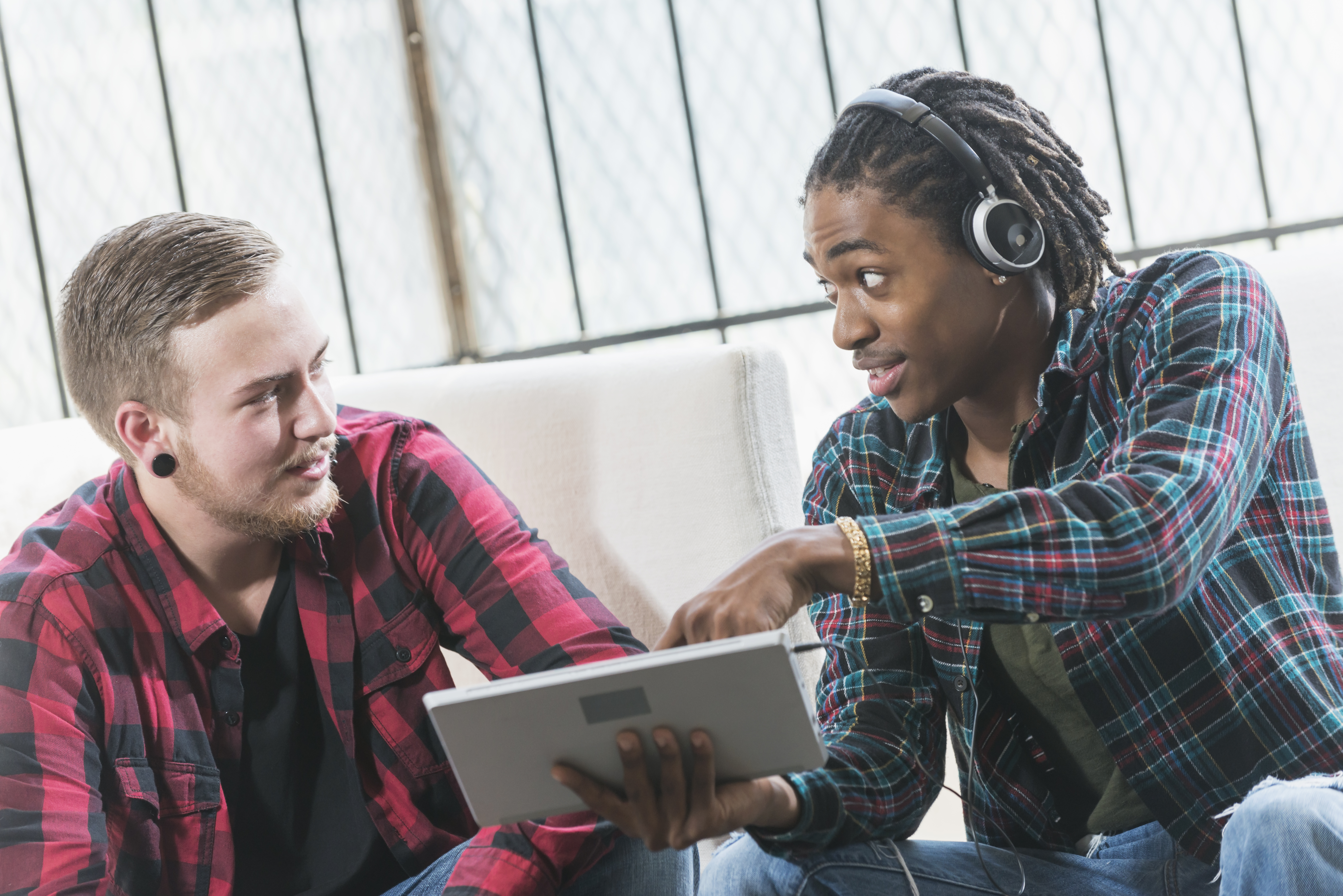 Two multi-ethnic young men discussing tablet computer