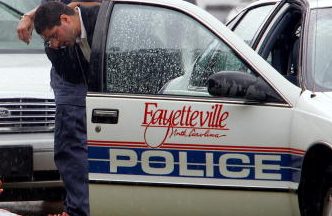 Police officers stand over a bloodied Miguel Carrasquillo on