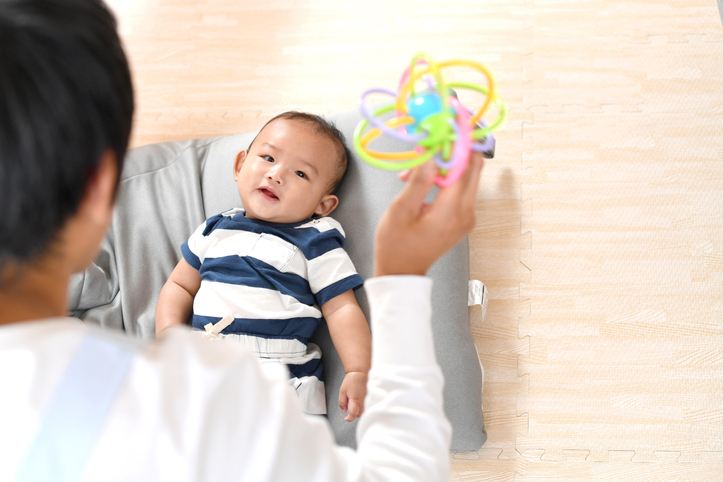 Rear view of a man soothing an Asian baby with a toy