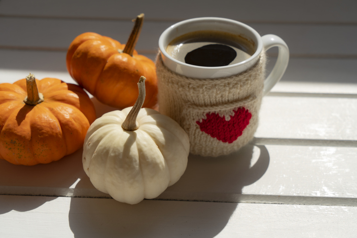Coffee cup on wooden table with pumpkins