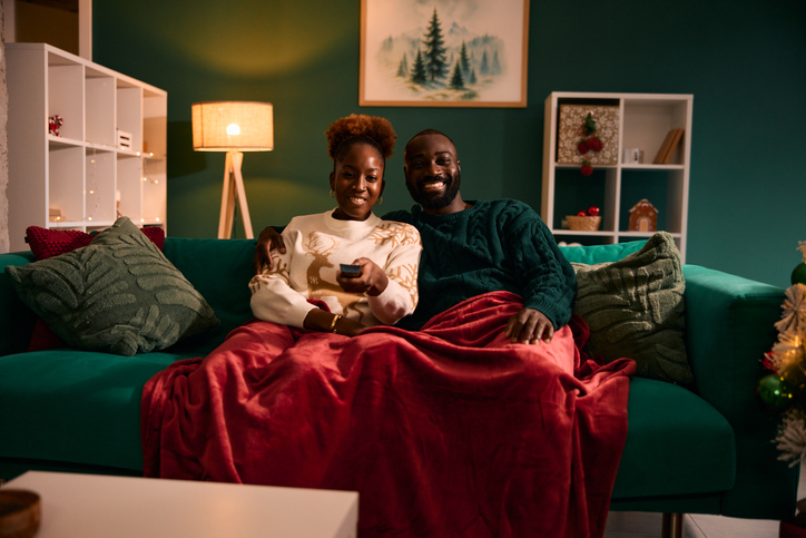 Black couple watching TV celebrating Christmas at home