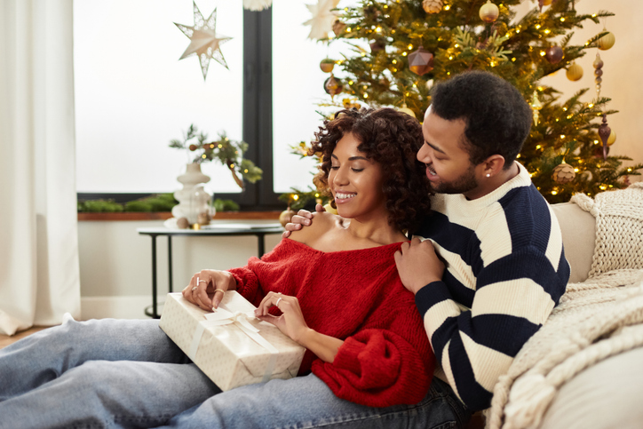 Happy couple celebrating Christmas in their cozy modern home with a festive tree